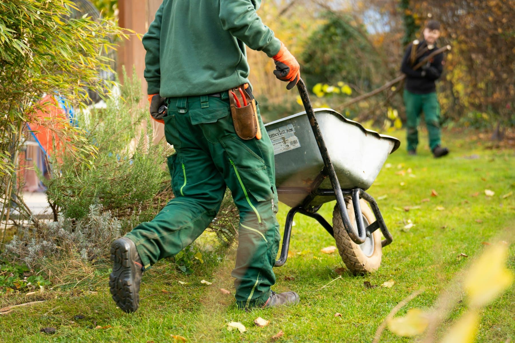 BEISPIEL-FOTO: Gärtner in Arbeitskleidung mit Schubkarre im Garten